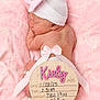 newborn, baby, sleeping, hat, bow, pink, blanket, wooden_sign, birth_announcement, ribbon, infant, soft_texture, closeup, cute, resting, skin, tiny, peaceful, portrait, person