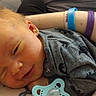 Henry is registered to the contest to win money with this photo: baby, infant, sleeping, pacifier, arm, wristbands, clothing, gray_onesie, person, resting, cute, newborn, skin, hand, face, smile, indoors, closeup, child, comfort