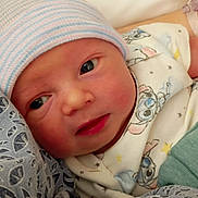 Henry is registered to the contest to win money with this photo: newborn, baby, infant, hat, clothing, patterned_clothing, bed, blanket, person, face, skin, cute, sleepwear, lying_down, indoors, child, newborn_hat, closeup, resting, soft