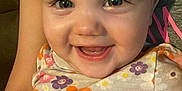Hayley joined the competition — help win amazing prizes! baby, smiling, child, flower_pattern, clothing, person, face, happy, cute, infant, portrait, sitting, colorful, young_child, eyes, skin, head, arm, holding, indoor