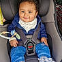 baby, child, car_seat, seat_belt, smile, curly_hair, pacifier, beaded_toy, jeans, sneakers, jacket, bib, buckle, safety, car_interior, happy, portrait, infant, cute, toddler