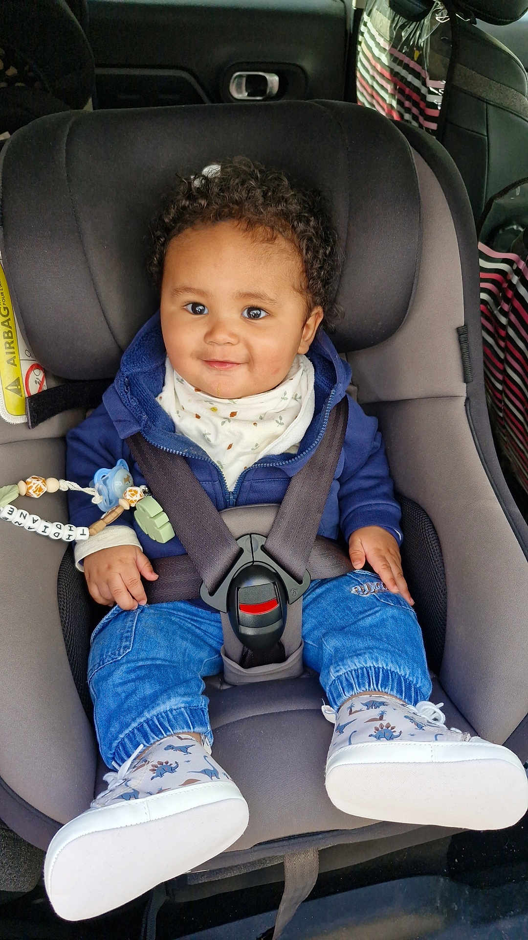 Tidiane participe au concours pour gagner de l'argent avec cette photo : baby, child, car_seat, seat_belt, smile, curly_hair, pacifier, beaded_toy, jeans, sneakers, jacket, bib, buckle, safety, car_interior, happy, portrait, infant, cute, toddler