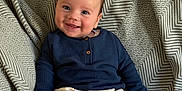 Oakley joined the competition — help win amazing prizes! baby, smiling, child, infant, sitting, blue_shirt, cream_pants, blanket, patterned_blanket, happy, cute, indoors, portrait, young_child, small_hands, footwear, cozy, comfortable, face, person