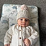 Oakley joined the competition — help win amazing prizes! baby, infant, knit_hat, pom_pom, sweater, buttoned_clothing, dinosaur_pattern, cushion, floor, carpet, indoor, portrait, cute, child, face, hands, warm_clothing, soft_texture, expression, lying_down