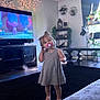 Violet joined the competition — help win amazing prizes! toddler, child, pacifier, barefoot, living_room, carpet, dress, television, animated_show, furniture, shelf, plant, curtains, window, light, decor, home, toy, person, indoor