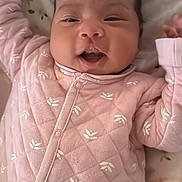 Zoey joined the competition — help win amazing prizes! baby, infant, newborn, onesie, pink, smiling, face, eyes, mouth, blanket, floral_pattern, quilted, pajamas, cute, chubby_cheeks, closeup, portrait, hand, bedding, cozy
