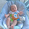 baby, infant, child, bouncer, seated, outdoor, porch, deck, railing, plush_toy, stuffed_animal, toy, blanket, white_clothing, bare_feet, smiling, face, portrait, backyard, daylight