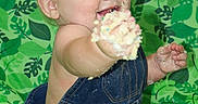 Oliver is registered to the contest to win money with this photo: baby, blue_eyes, cake, celebration, child, cute, denim_overalls, face, food, frosting, green_background, hand, happy, indoor, leaf_pattern, messy, one_year_old, portrait, sitting, smiling