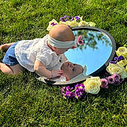 Polina is registered to the contest to win money with this photo: baby, child, reflection, mirror, grass, flowers, headband, outdoor, sunlight, white_blouse, purple_flowers, white_flowers, nature, portrait, curious, crawling, grass_field, closeup, baby_girl, spring