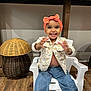 Merlyn joined the competition — help win amazing prizes! toddler, child, smiling, headband, orange, jacket, floral, jeans, white_chair, indoor, wicker_basket, wood_floor, happy, cute, person, sitting, home_decor, playful, young_child, bright