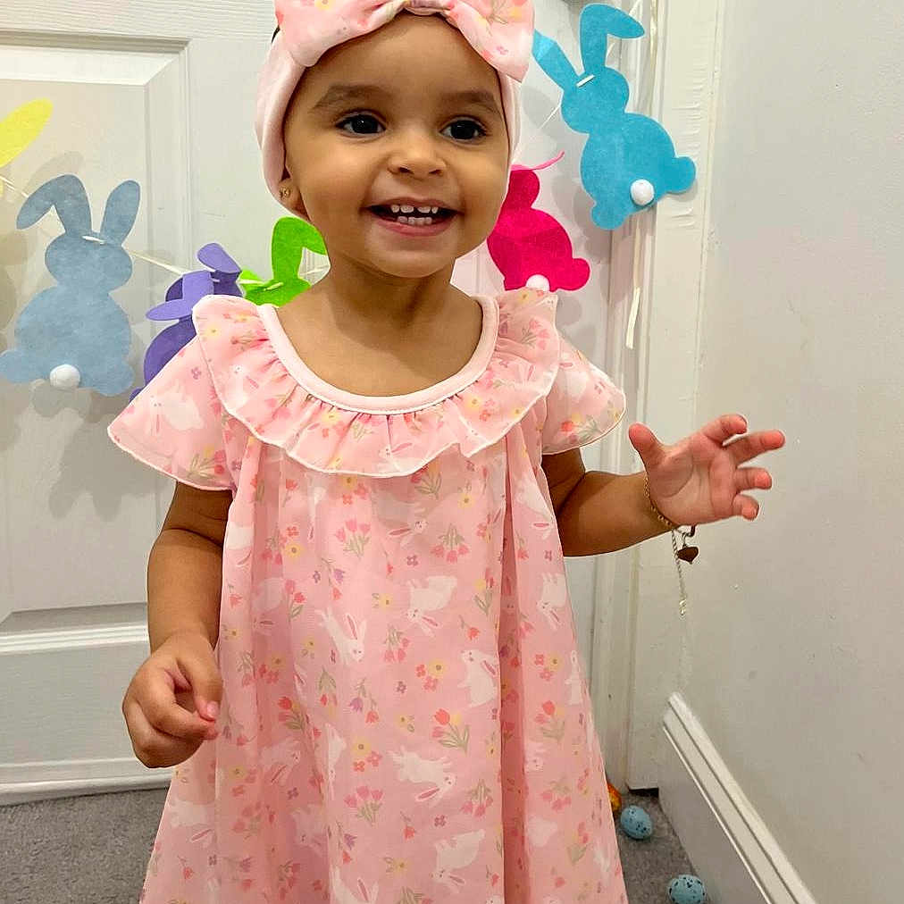 Merlyn joined the competition — help win amazing prizes! accessory, bow, bunny_decorations, carpet, celebration, child, cute, door, easter_eggs, happy, headband, holiday, indoors, jewelry, person, pink_dress, playful, portrait, smiling, toddler
