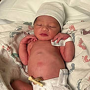 Eve is registered to the contest to win money with this photo: newborn, baby, infant, diaper, blanket, hospital, hat, umbilical_clamp, id_bracelet, sleeping, skin, cute, small, lying_down, indoors, footprints, tender, peaceful, child, person