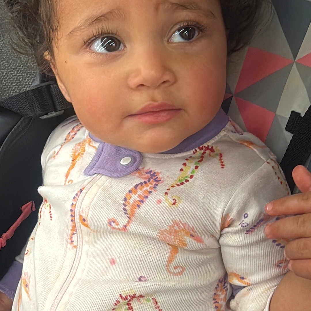Lilithivette is registered to the contest to win money with this photo: toddler, child, car_seat, onesie, seahorse_pattern, curly_hair, expressive_eyes, baby_clothing, indoor, seat_belt, colorful, geometric_pattern, candid, portrait, young_child, cute, person, sitting, car_interior, closeup