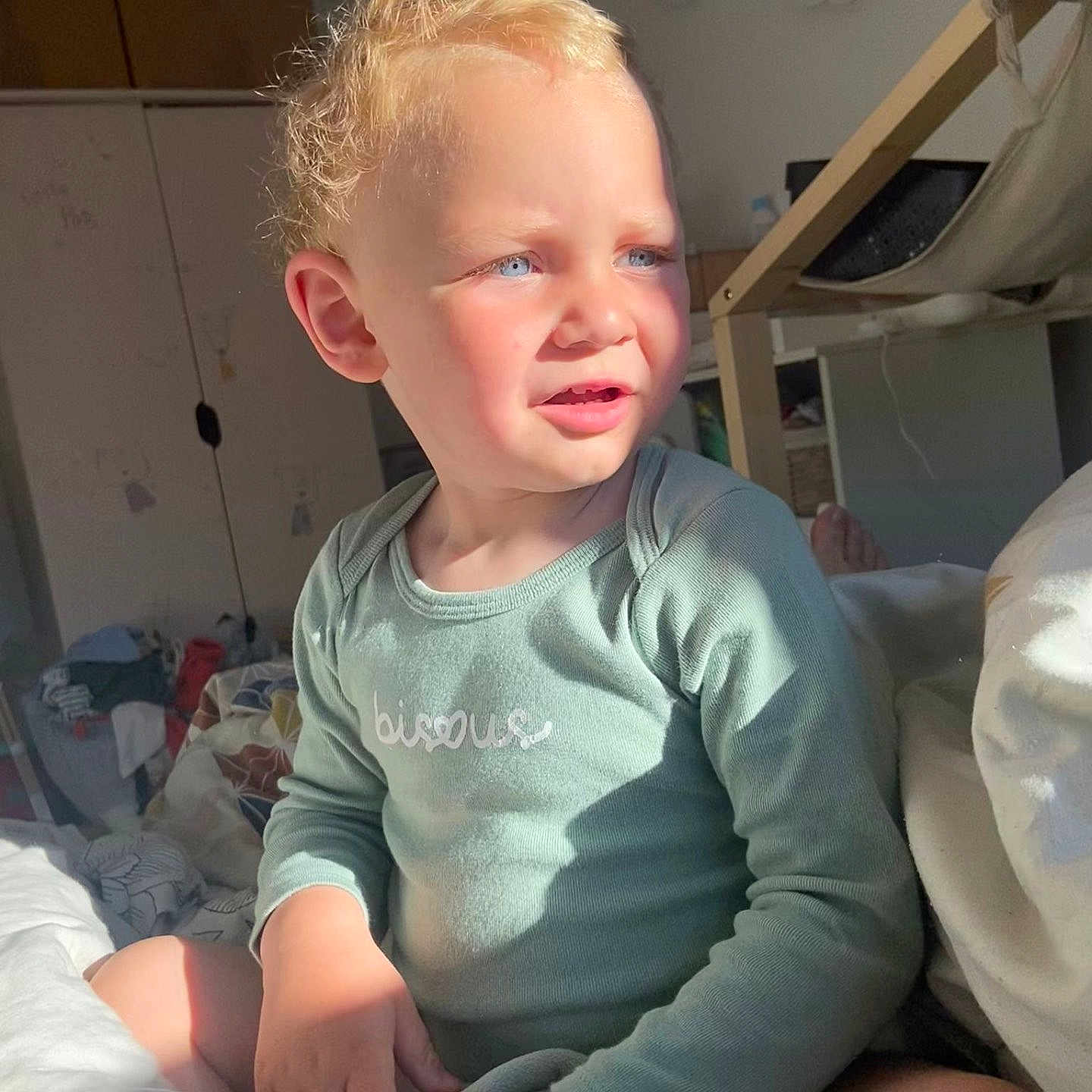 Ange participe au concours pour gagner de l'argent avec cette photo : blonde_hair, blue_eyes, casual_clothing, child, cozy, curly_hair, cute, daylight, expression, green_shirt, home_interior, indoor, person, portrait, relaxed, sitting, soft_light, sunlight, toddler, young_child