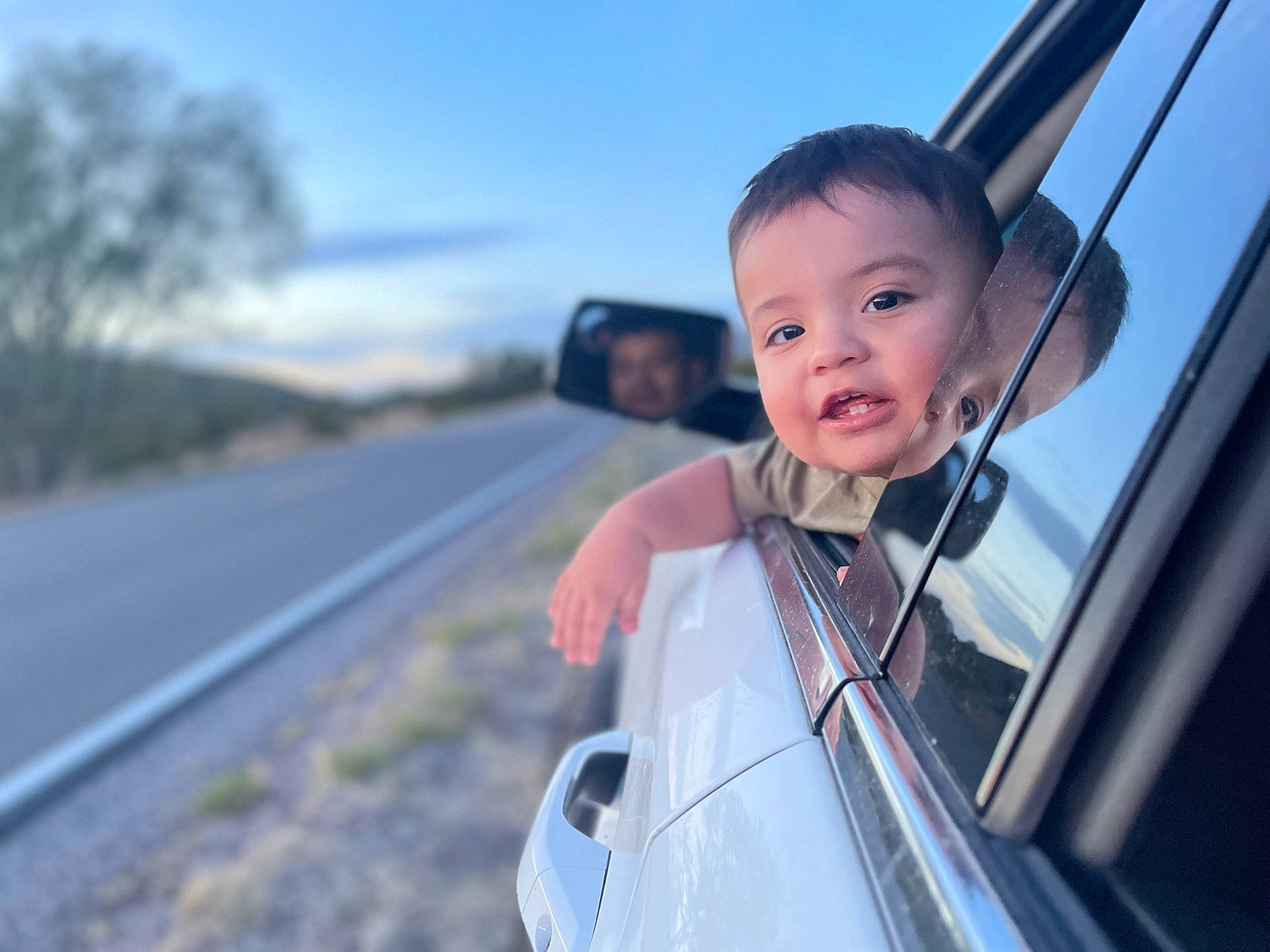 Jaime is registered to the contest to win money with this photo: automotive_design, automotive_exterior, automotive_lighting, automotive_mirror, automotive_tire, blurred, bumper, car, cloud, hood, mammal, mode_of_transport, motor_vehicle, person, plant, rear_view_mirror, sky, smile, tire, tree