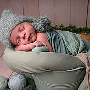 Raphaël a rejoint le concours — aidez-le/la à gagner de superbes lots ! newborn, baby, sleeping, hat, blanket, bucket, cozy, wrapped, indoors, soft_lighting, bokeh, decor, wooden_floor, cute, peaceful, infant, portrait, resting, green, warm