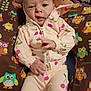 baby, child, hoodie, clothing, pattern, cherry, pillow, owl, colorful, cute, expression, face, hand, sitting, infant, indoors, fabric, soft, playful, portrait