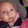 baby, infant, blue_eyes, car_seat, blanket, pink_clothing, face, child, safety_harness, close_up, cute, portrait, indoor, young_child, soft_texture, warm_clothing, seat, child_safety, warning_label, expression