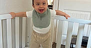 Ricardo joined the competition — help win amazing prizes! baby, bedding, bib, carpet, child, clothing, crib, dinosaur_pattern, door, happy, indoor, plush_toy, room, shorts, smiling, sock, toddler, toy, white_crib, window