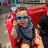 baby, child, sunglasses, shopping_cart, red, store, aisle, mannequin, clothing, floor, smile, seat, strap, blue, person, indoor, shopping, retail, cute, happy
