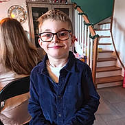 Héllyotte participe au concours pour gagner de l'argent avec cette photo : child, boy, glasses, smile, indoor, staircase, garland, person, furniture, cabinet, chair, hair, clothing, portrait, home, happy, casual, background, light, face