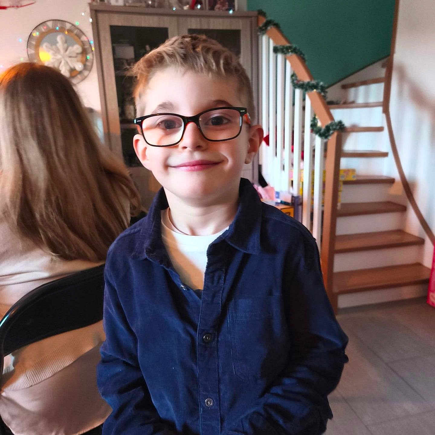 Héllyotte participe au concours pour gagner de l'argent avec cette photo : child, boy, glasses, smile, indoor, staircase, garland, person, furniture, cabinet, chair, hair, clothing, portrait, home, happy, casual, background, light, face