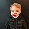 child, laughing, black_jacket, happy, light_hair, face, portrait, smile, young, person, indoor, cute, joy, emotion, clothing, puffer_jacket, childhood, casual, expression, background