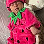baby, sleeping, strawberry_costume, pink, green, basket, blanket, pillow, soft, cute, infant, child, face, hand, cozy, resting, wearing, fabric, indoor, portrait