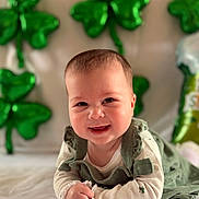 Hazel is registered to the contest to win money with this photo: baby, balloons, celebration, chubby_cheeks, clover, cute, face, green_balloons, green_outfit, hands, indoor, infant, lying_down, onesie, portrait, shamrock, smiling, soft_lighting, st_patricks, tummy_time