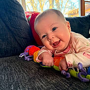 Hazel joined the competition — help win amazing prizes! baby, infant, smiling, couch, toy, colorful, indoors, window, daylight, face, child, happy, playing, hand, furniture, portrait, cute, expression, clothing, home