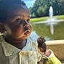 toddler, child, portrait, outdoor, pond, fountain, greenery, sunny, daylight, curly_hair, shirt, yellow_dress, nature, water, reflection, person, background_blur, closeup, expression, summer