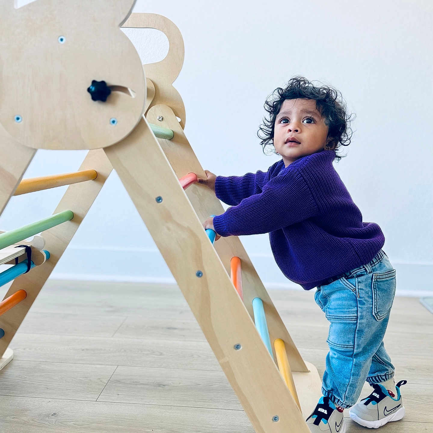 Vayu joined the competition — help win amazing prizes! activity, baby, child, climbing, colorful, curly_hair, cute, floor, footwear, indoor, jeans, looking_up, person, play, purple_sweater, sneakers, toddler, toy, wooden_climbing_frame, young_child