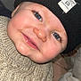 baby, child, blue_eyes, smile, knitted_sweater, beanie, black_hat, close_up, face, cheeks, cute, portrait, indoor, warm_clothing, infant, happy, person, headwear, toddler, skin