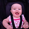 baby, child, smiling, happy, blue_eyes, onesie, floral_pattern, pink, stroller, seatbelt, infant, cute, portrait, baby_clothing, baby_girl, hands, face, cheerful, child_care, sitting