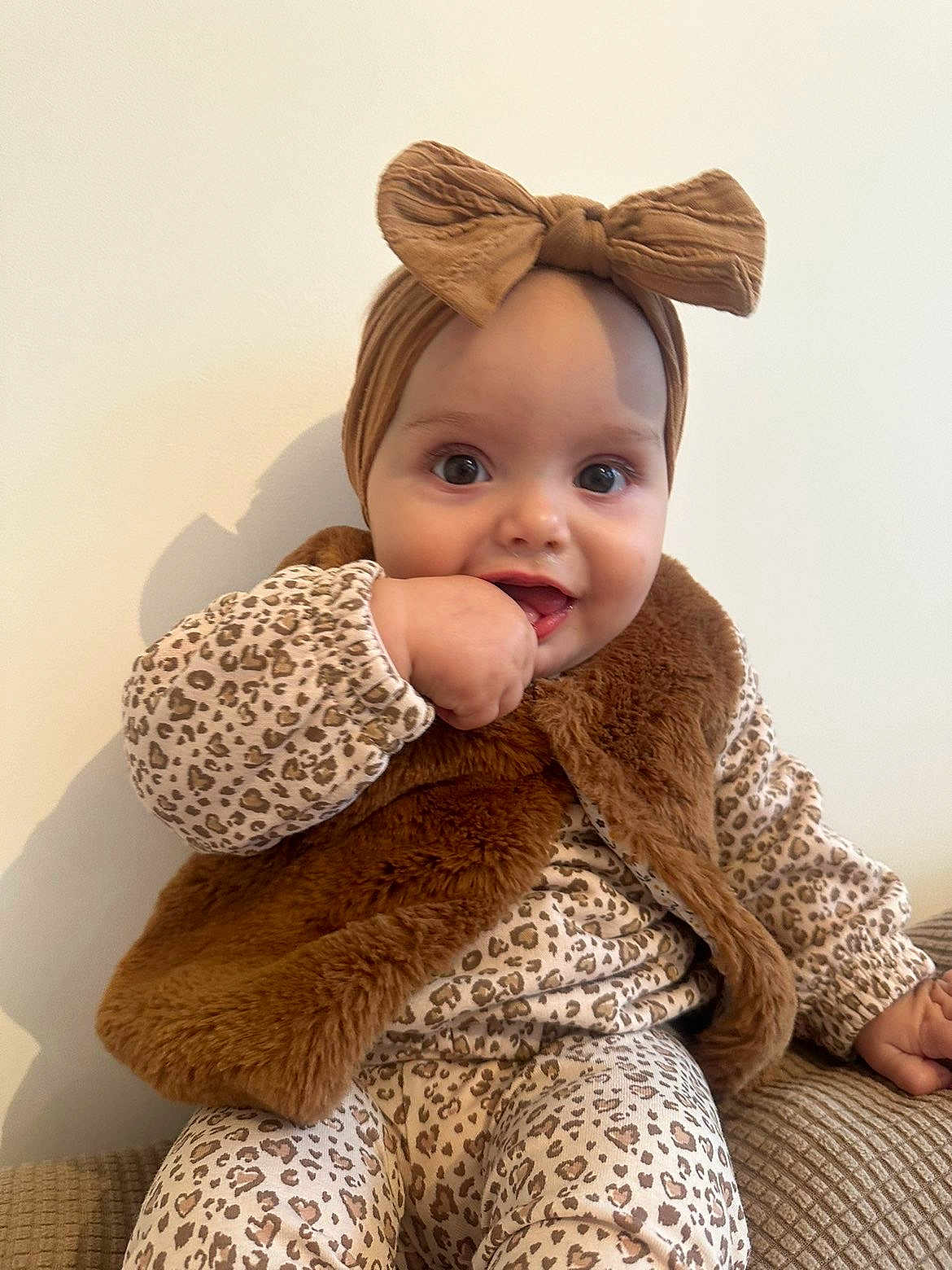 Haïlie a rejoint le concours — aidez-le/la à gagner de superbes lots ! baby, child, headband, bow, fur_vest, leopard_print, clothing, couch, hand, face, eyes, sitting, cute, infant, fashion, portrait, indoor, smiling, young_child, person