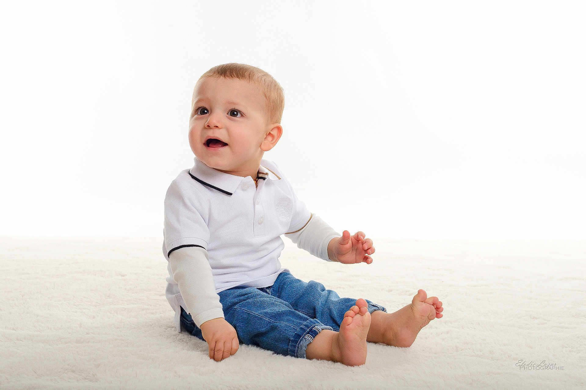 Lorenzo a rejoint le concours — aidez-le/la à gagner de superbes lots ! child, baby, toddler, portrait, studio, white_background, sitting, smile, cute, casual_clothing, polo_shirt, jeans, bare_feet, carpet, looking_up, expressive_face, hands, feet, indoor, bright_lighting