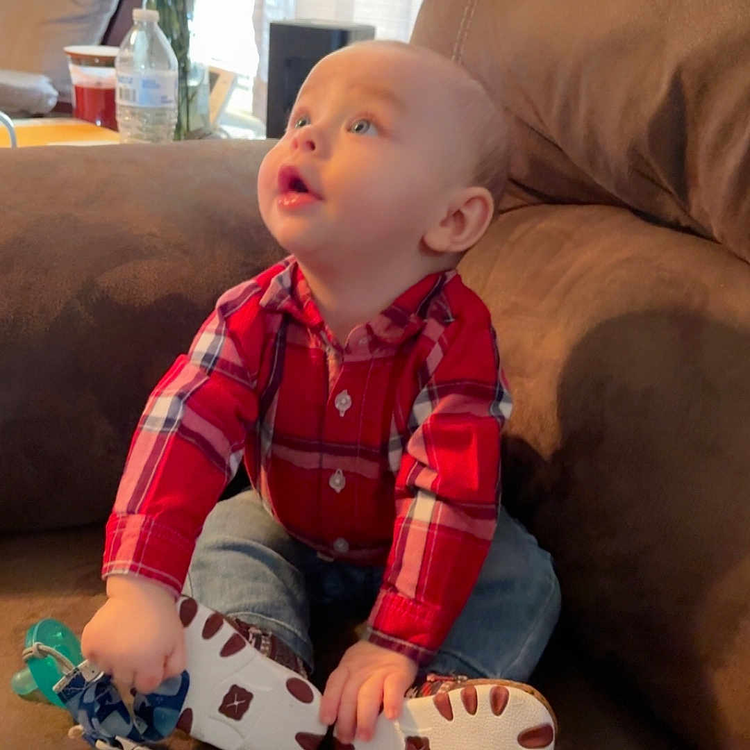 Zechariah joined the competition — help win amazing prizes! baby, brown, casual_clothing, child, couch, curious, expression, face, flowers, furniture, hands, home, indoor, jeans, looking_up, pacifier, plaid_shirt, sitting, toy, vase