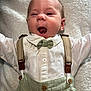 Knox is registered to the contest to win money with this photo: baby, infant, face, smile, yawn, clothing, shirt, bow_tie, suspenders, green, white, button, lying_down, blanket, texture, happy, cute, portrait, child, person