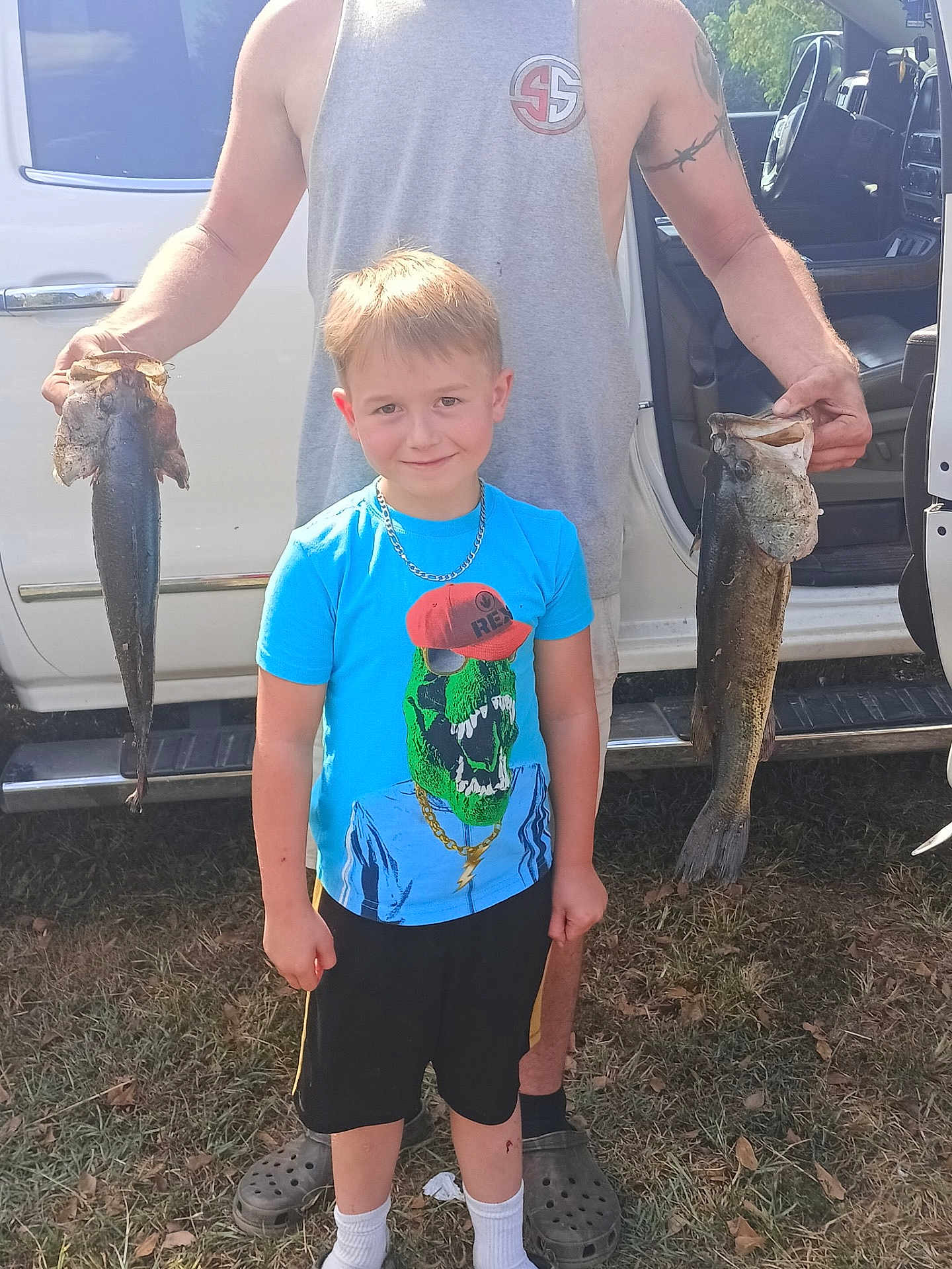 Hunter joined the competition — help win amazing prizes! boy, child, man, fish, fishing, outdoor, grass, truck, tshirt, shorts, socks, shoes, tattoo, summer, smile, necklace, vehicle, person, nature, catch
