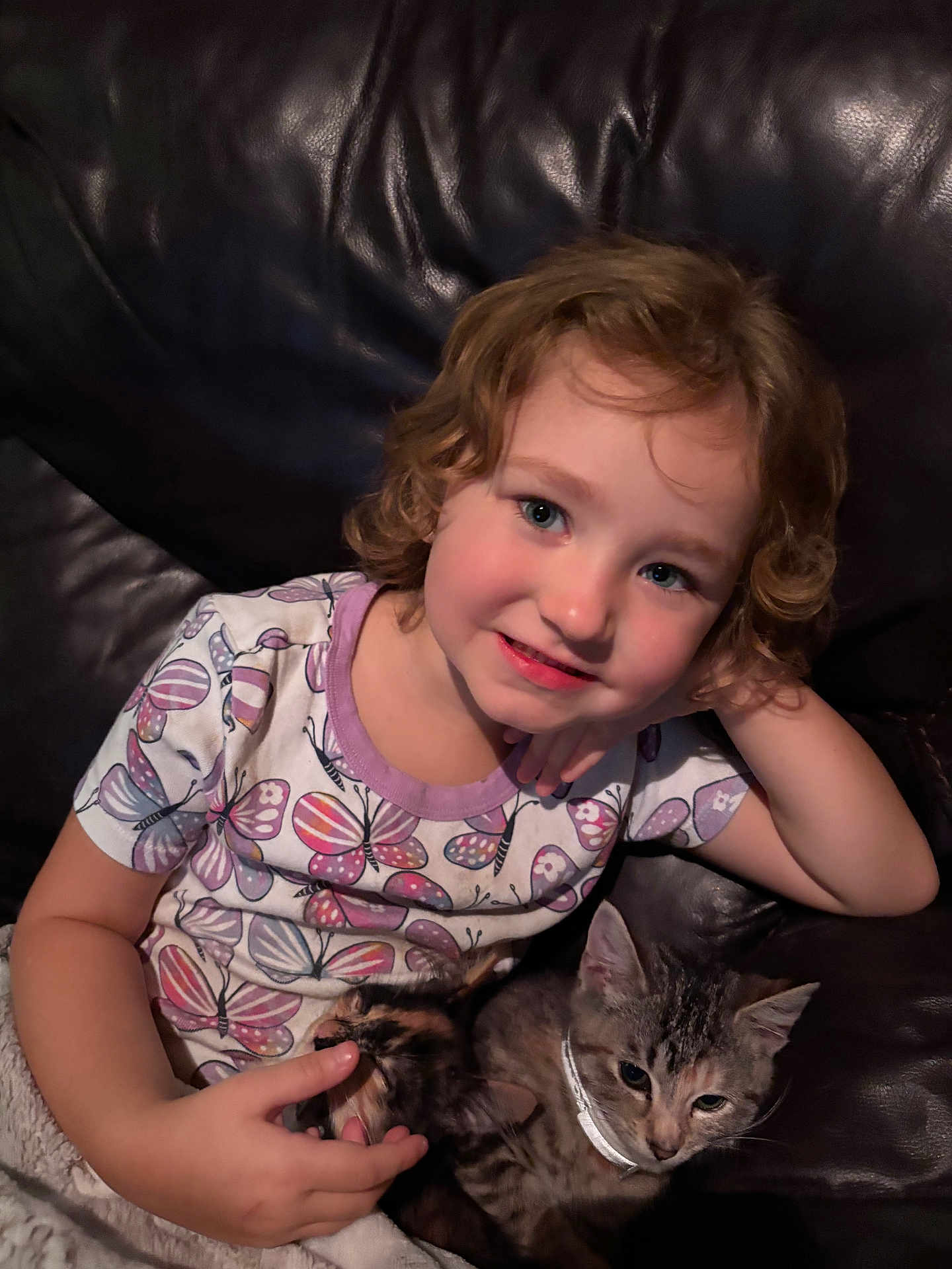 Haisley Mae joined the competition — help win amazing prizes! child, curly_hair, smile, couch, leather, cat, pets, collar, indoor, portrait, cozy, cute, person, relaxing, animal, feline, comfort, happy, casual_clothing, butterfly_pattern