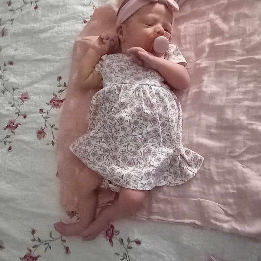Laura is registered to the contest to win money with this photo: baby, bed, bedroom, blanket, bodypart, bonnet, cap, clothing, dress, face, finger, furniture, hand, hat, head, newborn, person, photography, portrait, sleeping