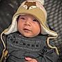 Mahé a rejoint le concours — aidez-le/la à gagner de superbes lots ! baby, hat, fox_design, cozy, embroidered_clothing, dark_outfit, infant, cute, face, hand, blue_eyes, portrait, warm_clothing, child, indoors, closeup, soft_lighting, seated, expression, person