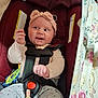 baby, car_seat, headband, pink, smiling, happy, infant, child, toy, clothing, seatbelt, cute, patterned_pants, floral, blanket, indoors, person, safety, hand, face