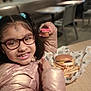 Delilah joined the competition — help win amazing prizes! child, girl, glasses, pigtails, smile, thumbs_up, candy, cheeseburger, french_fries, food, tray, jacket, indoor, restaurant, table, happy, casual_dining, person, meal, snack