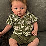 baby, child, infant, hair, green_shirt, shorts, sitting, couch, curious, blue_eyes, portrait, indoor, clothing, cute, young, person, expression, skin, casual, comfortable