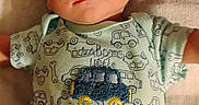 Timothy joined the competition — help win amazing prizes! baby, infant, child, portrait, lying_down, indoors, blanket, striped_blanket, onesie, toy_car, vehicle_pattern, gray_pants, dark_hair, wide_eyes, serious_expression, looking_at_camera, close_up, warm_lighting, textile, cozy