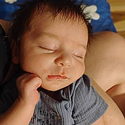 Timothy is registered to the contest to win money with this photo: newborn, baby, sleeping, infant, portrait, face, closed_eyes, peaceful, gray_clothing, blanket, blue_blanket, stars, caregiver, indoors, close_up, soft_lighting, dark_hair, hand, cozy, resting
