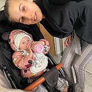 Lya a rejoint le concours — aidez-le/la à gagner de superbes lots ! baby, bottle, child, clothing, face, female, floor, furniture, hat, indoor, jacket, person, plaid, pose, smile, stroller, table, toddler, woman, young
