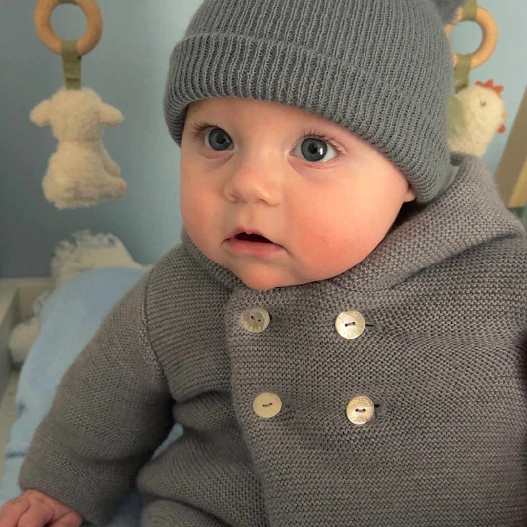 Raphaël participe au concours pour gagner de l'argent avec cette photo : baby, child, knit_hat, pom_poms, grey_sweater, buttons, blue_blanket, plush_toys, indoor, cute, curious, infant, soft_toys, wooden_rings, face, portrait, warm_clothing, seated, baby_clothes, adorable