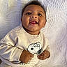 baby, child, infant, smiling, happy, portrait, lying_down, blanket, bed, sweatshirt, clothing, snoopy, cartoon, hands, face, eyes, mouth, indoor, close_up, photography